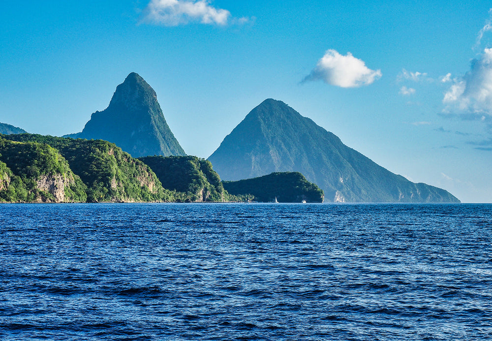 Scenic view of the Pitons, two mountainous volcanic spires, rising above the blue Caribbean Sea in Saint Lucia.